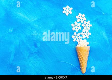 Eiscreme-Form aus einem Waffelkegel und gefälschten Show Flocken in der unteren rechten Ecke eines blauen strukturierten Hintergrund mit Kopierraum platziert. Stockfoto
