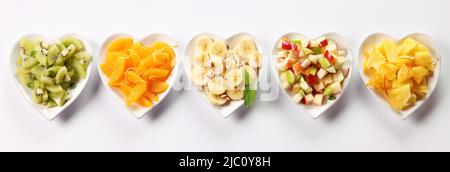 Verschiedene in Scheiben geschnittene Früchte in herzhaften Schüsseln auf isoliertem weißem Hintergrund Stockfoto