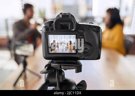 Nahaufnahme von professionellen Kamera-Aufnahme Podcast Interview von zwei Bloggern. Mann und Frau Podcasters in Kopfhörern sprechen miteinander, während sie Video-Podcast oder Vlog im Rundfunkstudio drehen Stockfoto