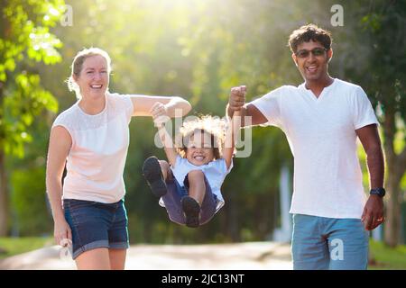 Familienspaziergängen im Sommerpark. Eltern und Kinder im Freien. Mutter, Vater und Kinder spielen, lachen, picknicken im sonnigen Garten. Stockfoto