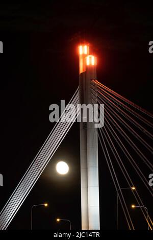 Der Mond steigt hinter der „Lumberjack's Candle Bridge“ in Rovaniemi, Lappland, Finnland. Stockfoto