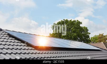 Die helle Sonne spiegelt sich in einer modernen Solaranlage auf dem Hausdach wider Stockfoto