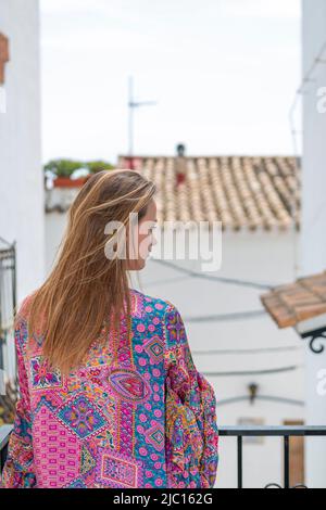 Frau von hinten auf dem Balkon mit Blick auf die ländliche Dorfstraße Stockfoto