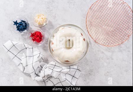 Flach liegend. Lasuring frisch gebackenen Bundt Kuchen mit Vanille-Glasur. Stockfoto