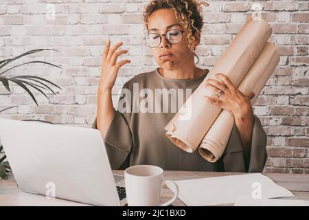 Gestresste und müde Frau überarbeite Online-Aktivitäten vor einem Laptop, der Papierdokumente hält. Weibliche Erwachsene Menschen unzufrieden über ihren Job. Smar Stockfoto