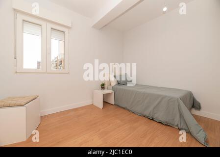 Schlafzimmer mit Einzelbetten mit grauen Federdecken, weißen Möbeln und weißen Aluminiumfenstern mit Aussicht Stockfoto