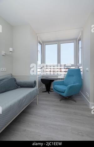 Ecke eines Zimmers mit einem blauen individuellen Sofa, Pavillon mit Aussicht und grauem Parkettboden Stockfoto