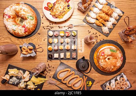 Set von Desserts, Süßigkeiten, Kuchen und Frühstück, Croissants mit Zucker, Käseplatte, Rosenkegel mit Creme, Churros mit Zucker und Schokolade Stockfoto