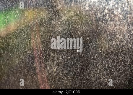 Plaque auf Glas im Frühjahr. Schmutzige Fensterdetails. Sonnenlicht auf staubiger Oberfläche. Stockfoto