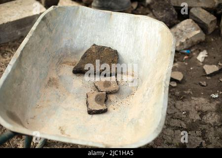 Wagen mit Steinen. Gartenwagen. Reinigung von Bauabfällen. Transport von gebrochenem Asphalt. Baumaterial in Russland. Stockfoto