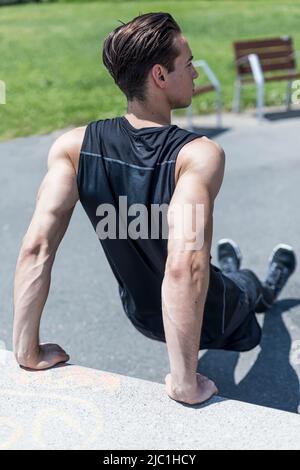 Fitness-Mann macht Bank Trizeps Dips während Outdoor-Cross-Training Workout. Stockfoto