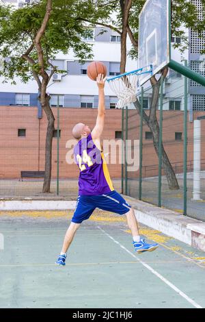 Ein junger Basketballspieler, der einen Basketball schießt Stockfoto