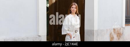 Die ganze Länge der jungen Rotschopf Frau in Kleid zu Fuß mit der Hand in der Tasche auf der Straße in valencia, Banner Stockfoto