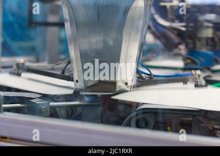 Nahaufnahme von kartografischen Industriemaschinen bei der Arbeit in einer Produktionslinie, Förderbänder sind sichtbar, keine Menschen sind anwesend. Stockfoto