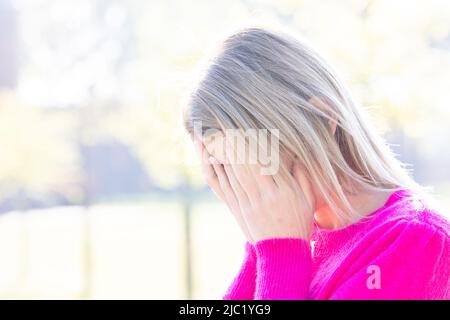 Müde, traurig oder deprimiert junge schöne blonde Frau vergräbt ihr Gesicht in ihren Händen Angst, mit Angstanfall oder Kopfschmerzen Migräne oder Depressionen, verärgert frustriertes Mädchen mit Problem bekümmert fühlen sich gestresst Abdeckung weinendes Gesicht mit der Hand leiden Trauer Trauer Konzept. Hochwertige Fotos Stockfoto