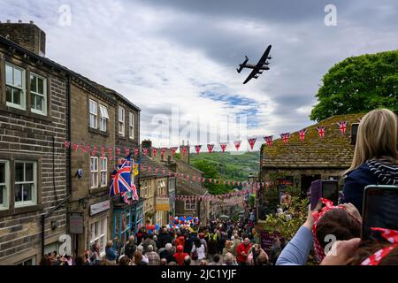 Haworth 1940er-Wochenende (geschäftige, überfüllte Main Street, dekoriert in Union Jacks, beobachten eines historischen Flugzeugs, jährliche Veranstaltung) - West Yorkshire, England, Großbritannien. Stockfoto