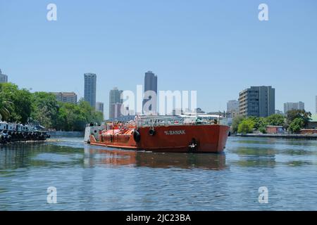 Manila, Philippinen: Frachtschiff überquert den sanierten Pasig River in Richtung der Gebäude der dicht besiedelten, stark urbanisierten Hauptstadt. Stockfoto