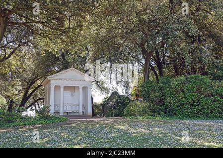 Der weiße Thomson Seat im Mount Edgcumbe Park, Rame, Cornwall blickt von seiner hübschen bewaldeten Umgebung und der Daisy Cove auf die geschäftige Hamoaze und den Fluss Tamar Stockfoto