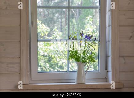 Weißes Fenster mit Mosuito-Netz in einem rustikalen Holzhaus Stockfoto