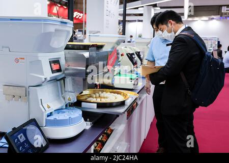 Tokio, Japan. 9.. Juni 2022. Besucher sehen sich Sushi-Maschinen während der Internationalen Messe für Lebensmittelmaschinen und -Technologie (FOOMA JAPAN) im Tokyo Big Sight in Tokio an. Die jährliche Ausstellung stellt die neuesten Produkte und Dienstleistungen für die Lebensmittelverarbeitung in 8 Hallen vor. FOOMA JAPAN läuft vom 7. Bis 10. Juni. (Bild: © Rodrigo Reyes Marin/ZUMA Press Wire) Stockfoto