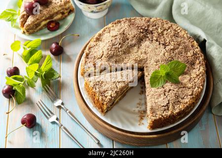 Hausgemachtes Sommergebäck glutenfrei. Schokoladen- und Quark-Kuchen mit Kirschen auf einem rustikalen Tisch. Stockfoto