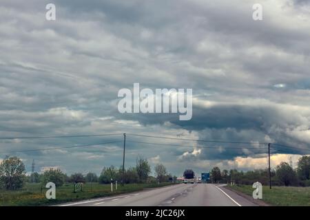 Gerade asphaltierte Straße mit Markierungen, die in die Ferne durch Stockfoto