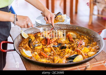 Serviert werden traditionelle spanische Paella mit Meeresfrüchten aus der Bratpfanne mit Muscheln, Kaisergranat und Fisch Stockfoto