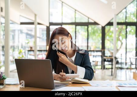 Foto Geschäftsfrau trägt moderne weiße Hemd, Gespräch Smartphone mit Buchhalter Beratung und halten Stift für die Berechnung der Steuer, Finanzbericht Stockfoto