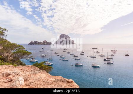 Verankerte Katamarane und Segelyachten in der Bucht Cola d'Hort vor dem Hintergrund der beiden schönen felsigen Inseln Es Vedra und Es Vedranell. Ibiza, Balearen Isla Stockfoto