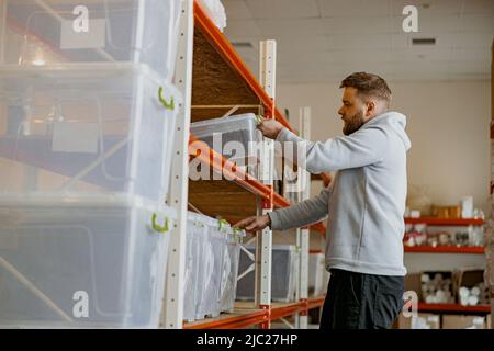 Unternehmer stapelt Kisten mit gerösteten Kaffeebohnen in einem Regal in einem Lager Stockfoto