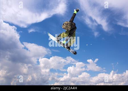 Snowboarder in Aktion, springen gegen blauen Himmel Stockfoto