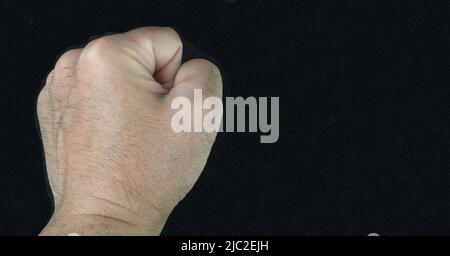 Die Faust eines Mannes auf einem schwarzen Hintergrund.Protestkonzept.Bewegung der Schwarzen lebt Materie. Stockfoto