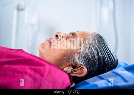 Handgeführte Nahaufnahme der weinenden kranken älteren älteren Frau auf dem Krankenhausbett - Konzept von ungesund, Leid und Trauer Stockfoto