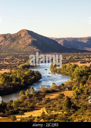 Blick über den Vaal River, der durch die hügeligen Hügel des Vredefort Dome in Südafrika fließt Stockfoto