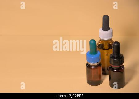 Braune Flaschen mit Droppern, ohne Branding, Textraum, gelblicher Hintergrund. Stockfoto