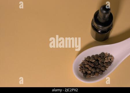 Braune Tropfflaschen mit Kräutern oder Gewürzen auf weißem Löffel, ohne Branding und mit korrekter Textfläche. Stockfoto