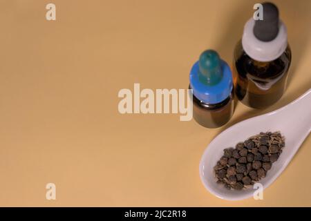 Braune Tropfflaschen mit Kräutern oder Gewürzen auf weißem Löffel, ohne Branding und mit korrekter Textfläche. Stockfoto