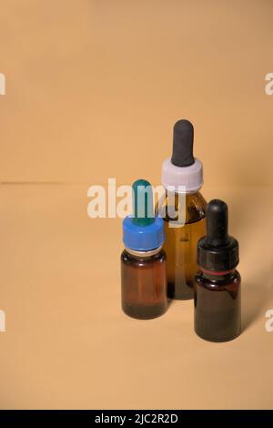 Braune Flaschen mit Droppern, ohne Branding, Textraum, gelblicher Hintergrund. Stockfoto