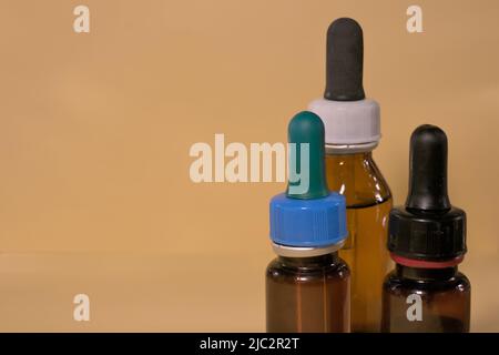 Braune Flaschen mit Droppern, ohne Branding, Textraum, gelblicher Hintergrund. Stockfoto