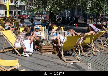 Ixelles, Brüssel Capital Region - Belgien - 06 22 2020 attraktives 18-jähriges Mädchen in weißer Spitze, das mit ihren Freunden die Sonne genießt Stockfoto