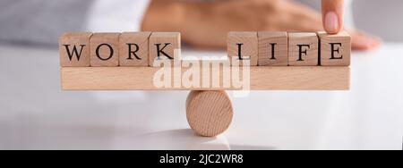 Nahaufnahme der Geschäftsmann, der mit dem Finger zeigen, Ungleichgewicht zwischen Arbeit und Leben auf hölzernen Wippe Stockfoto