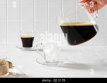 Kalter schwarzer Kaffee mit Eiswürfeln auf weißem Hintergrund. Sommergetränke. Platz kopieren Stockfoto