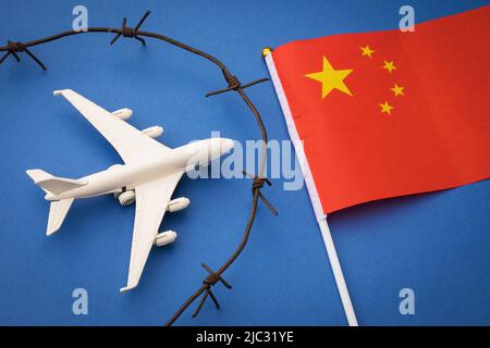 Spielzeugflugzeug, Flagge und rostiger Stacheldraht auf farbigem Hintergrund, China Air Border geschlossenes Konzept Stockfoto