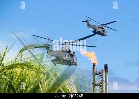 Militärhubschrauber fliegen über Weizenfeld und Gaskamin. Konzeptbild: Ukraine Russland-Konflikt, Weizen, Lebensmittelknappheit, russische Sanktionen... Stockfoto