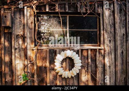 Holzmauer des Gartenschuhs mit einem Kranz aus Muschelschalen und einem Vogelhaus auf dem Long Hill Sedgwick Anwesen. Bild, das auf einem analogen Film aufgenommen wurde. Beverly, Massachus Stockfoto