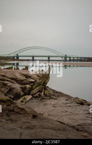 Schiffswrack am Sandstrand, Wigg Island, mit der Runcorn Bridge / Silver Jubilee Bridge im Hintergrund - Runcorn, Großbritannien. Stockfoto