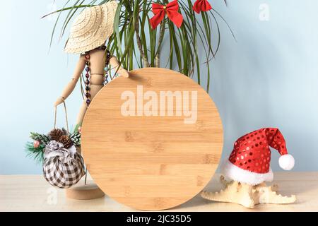 Weihnachten im Juli Holz rund Zeichen mockup im Urlaub Sommer Strand Hintergrund. Sommerurlaub. Holzfigur eines Mannes in einem Korbhut und Perlen. Happ Stockfoto