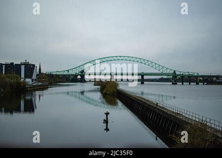 Runcorn Bridge / Silver Jubilee Bridge in Runcorn, Großbritannien, reflektiert im Wasser. Stockfoto