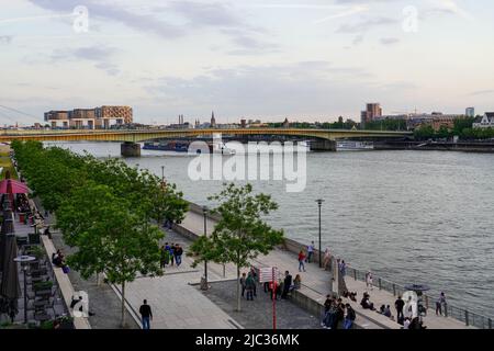 Menschen an der Uferpromenade des Rheins. Rheinauhafen mit Kranhäusern in Köln, Nordrhein-Westfalen, Deutschland, 21.5.22 Stockfoto