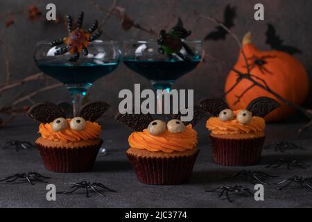 Halloween Treat - Helle süße Kuchen in Form von Fledermäusen auf braunem Hintergrund mit Dekor Stockfoto